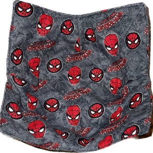 May include: A gray fabric square with a repeating pattern of red Spider-Man faces and the text "The Amazing Spider-Man".