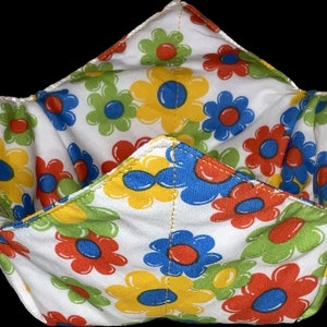 May include: A white fabric bowl with a floral pattern in shades of red, yellow, blue, and green. The bowl is folded into a cone shape.