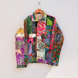 May include: A long-sleeve button-up jacket constructed from a vibrant patchwork of quilted fabric. The garment features a diverse array of colorful patterns, including tropical foliage, animal prints, and geometric shapes, finished with wooden buttons.