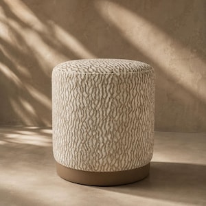 May include: A cylindrical ottoman featuring a textured, cream-coloured fabric with a vertical, wavy, light brown pattern. The base of the ottoman is constructed from a solid, smooth, light brown material that provides a stable foundation for the piece.