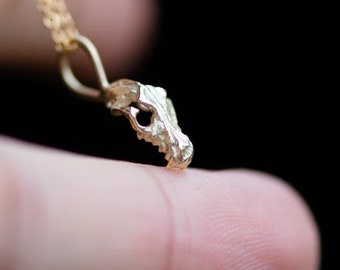 May include: A gold chain necklace with a small, detailed skull pendant.