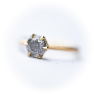 May include: A gold ring with a gray, hexagonal, rough-cut diamond.