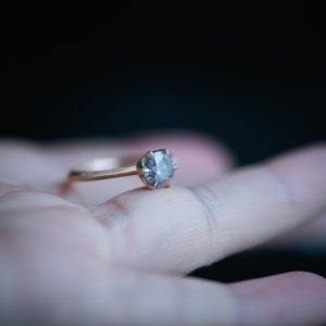 May include: A gold ring with a grey diamond-shaped stone set in the center.