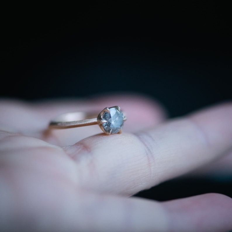 May include: A gold ring with a grey diamond-shaped stone set in the center.