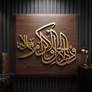 May include: A square wall art piece featuring gold-colored Arabic calligraphy mounted on a dark brown wood grain panel. The intricate, raised lettering creates a three-dimensional effect against the smooth, polished wooden surface of the square plaque.