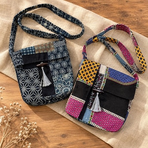 May include: Two square crossbody bags featuring patchwork designs. The left bag has blue and white geometric patterns. The right bag has colorful floral and polka dot patterns in yellow, pink, and blue. Both bags include a wooden toggle and tassel.