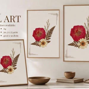 May include: Three framed wall art prints featuring pressed red and white flowers with brown ferns on a cream background. The text WALL ART and sizes A4, 20.3 x 25.4cm, and 40.6 x 50.8cm are visible. Each print includes thin black corner line accents.