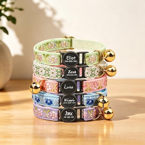 Peut inclure: Une pile de cinq colliers pour animaux en vert clair, blanc, rose, bleu et violet, chacun avec une broderie florale, une clochette dorée et une boucle en plastique noir gravée de noms comme Eliot, Zest, Luna, Kiwi et Jinx avec numéros.