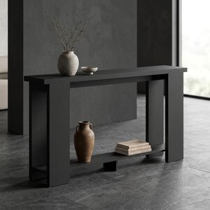 May include: A black console table with a rectangular top and a lower shelf. The top holds a textured light gray vase with thin branches and a small bowl. The lower shelf holds a brown ceramic vase and a stack of three light-colored books.