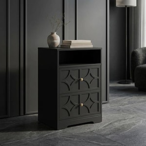 May include: A black nightstand featuring an open top shelf and two drawers with geometric circular patterns and small round light-colored knobs. A light-colored ceramic vase with thin branches and a stack of books sit on the top surface.