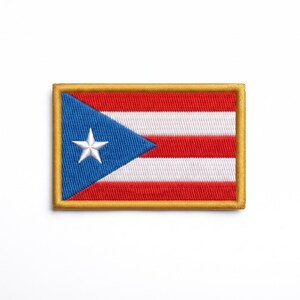 May include: A rectangular embroidered patch featuring the flag of Puerto Rico. The design includes three red horizontal stripes, two white horizontal stripes, a blue triangle on the left side, and a single white five-pointed star. Gold border.