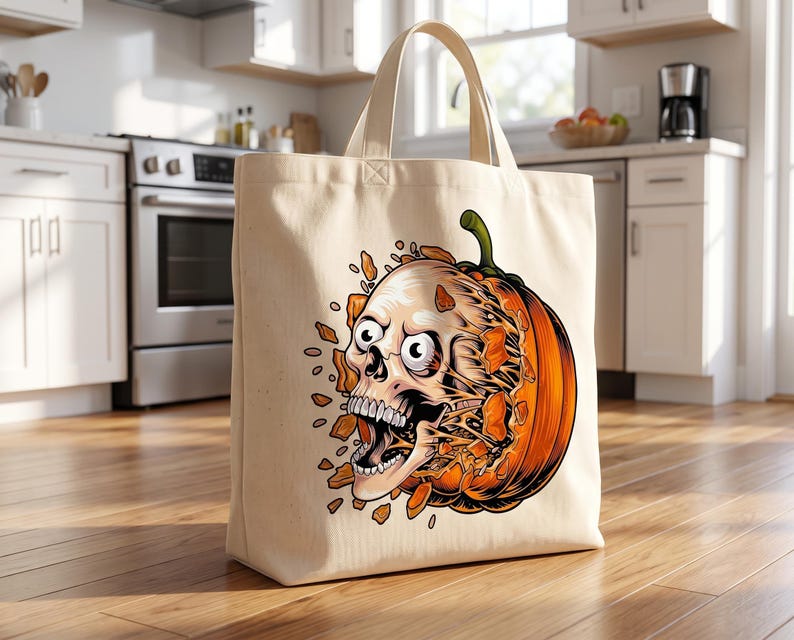 May include: A beige canvas tote bag featuring a graphic illustration of a human skull emerging from a bright orange pumpkin. The skull has wide, startled eyes and an open mouth, with orange pumpkin fragments scattered around the central design.