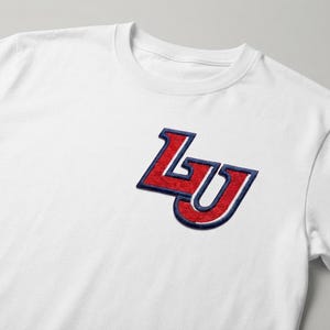 May include: A white short-sleeved t-shirt featuring an embroidered patch on the left chest. The patch displays the letters LU in a bold, stylized font, rendered in red with a thick navy blue outline and a white inner border detail.