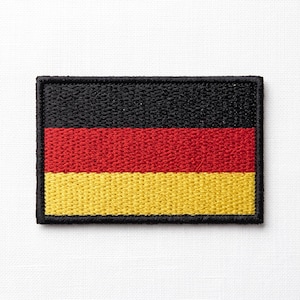Puede incluir: Un parche rectangular bordado que presenta la bandera tricolor horizontal de Alemania. El diseño consta de tres franjas horizontales iguales en negro en la parte superior, rojo en el medio y dorado en la parte inferior, todo con un borde negro.