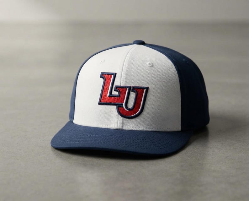 May include: A baseball cap featuring a white front panel and navy blue side and back panels. The front displays an embroidered red and navy blue logo with the letters LU. The cap has a navy blue brim and a button on the top center.