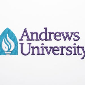 Op de afbeelding: Een geborduurde patch met de tekst Andrews University in paarse draad. Links van de tekst staat een blauwgroen, boogvormig embleem met een wit vlamontwerp. Het gehele ontwerp is gestikt op een effen witte stoffen achtergrond.