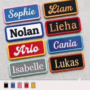 Może przedstawiać: Osiem prostokątnych haftowanych naszywek z imionami o różnych kolorach obramowań i tła. Naszywki zawierają imiona Sophie, Liam, Nolan, Lieha, Arlo, Cania, Isabelle i Lukas wykonane różnymi czcionkami i kolorami nici.