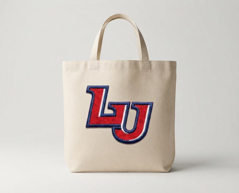 May include: A beige canvas tote bag featuring a large, embroidered patch on the front. The patch displays the letters LU in a bold, collegiate-style font with a textured red fill, a white outline, and a thick navy blue border.