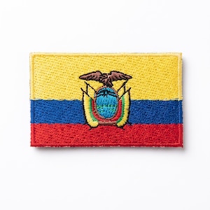 May include: A rectangular embroidered patch featuring the national flag of Ecuador. The design consists of horizontal yellow, blue, and red stripes with the national coat of arms centered, displaying an eagle, a mountain, and a sun in thread.