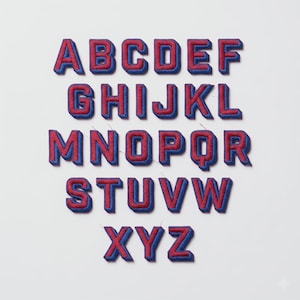 May include: A complete set of twenty-six embroidered alphabet letters from A to Z. Each individual letter patch features a bold red center with a thick, dark blue border, designed with a block-style font and a three-dimensional appearance.