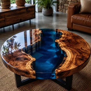 Peut inclure: Une table basse ronde composée d'une tranche de bois naturel aux bords irréguliers avec une finition brillante. Une incrustation centrale en résine bleu profond translucide traverse le bois. La table repose sur une base en métal noir.