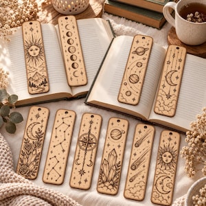 May include: A collection of ten rectangular wooden bookmarks featuring intricate laser-engraved designs including celestial bodies, suns, moons, planets, constellations, crystals, flowers, and a compass, each with a small hole at the top.