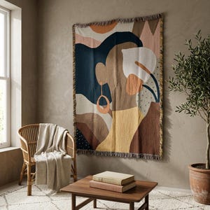 Puede incluir: Un tapiz de pared tejido rectangular que presenta un diseño gráfico abstracto de un perfil humano en tonos azul marino, terracota, amarillo mostaza, crema y marrón, acabado con un borde con flecos en los lados superior e inferior.