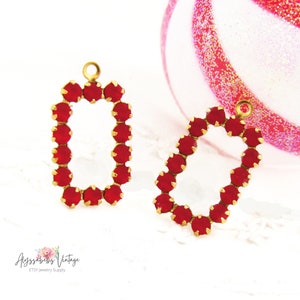 May include: Two gold-toned metal charms with a rectangular frame of red rhinestones. The charms have a loop at the top for attaching to jewelry.