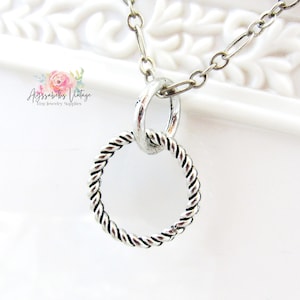 May include: Silver necklace with a twisted circle pendant. The pendant is attached to a silver chain.