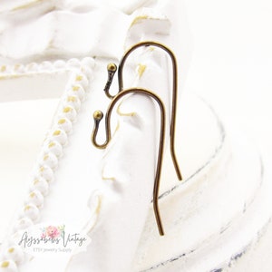 May include: Two antique brass earring hooks. The hooks are made of metal and have a smooth, rounded finish.