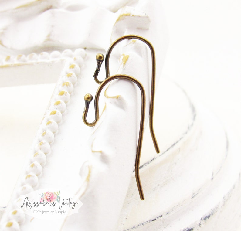 May include: Two antique brass earring hooks. The hooks are made of metal and have a smooth, rounded finish.