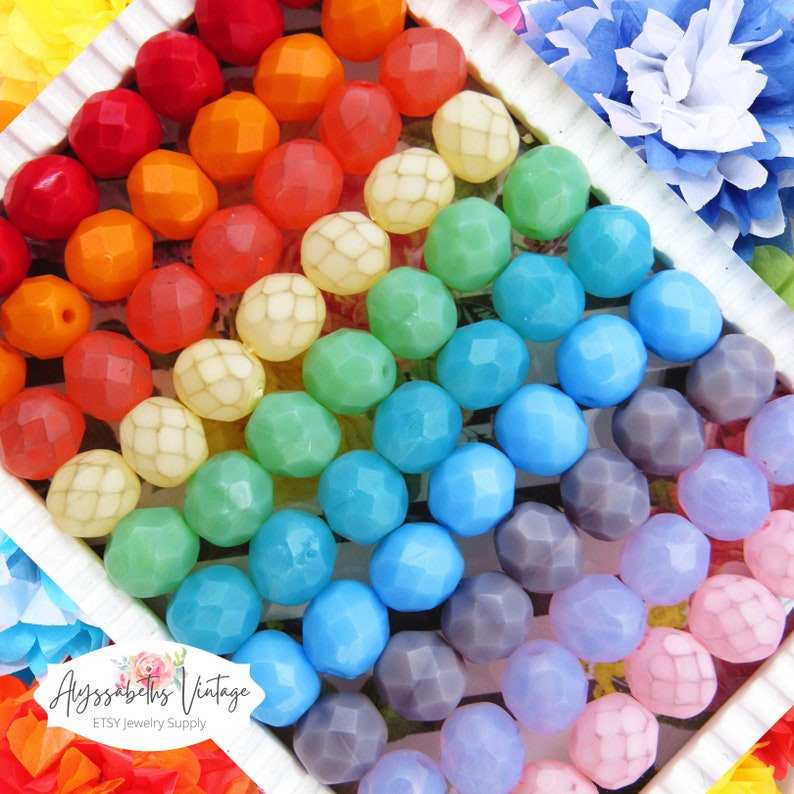 May include: Rainbow assortment of faceted glass beads. The beads are arranged in rows by color, starting with red and ending with pink. The beads are all approximately 10mm in diameter.