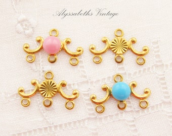 May include: Four gold-tone metal connector pieces with decorative swirls. Two pieces feature a pink glass bead and two pieces feature a turquoise glass bead.