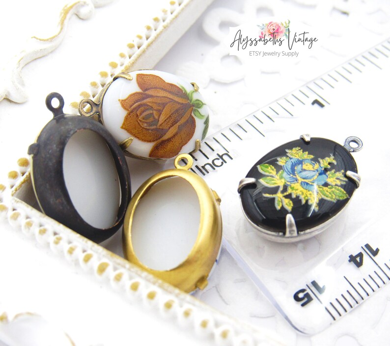 May include: Three oval-shaped metal locket pendants with floral designs. The lockets are in different colors: black, gold, and white. The lockets are about 1 inch in length.
