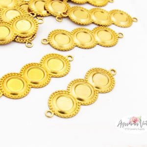 May include: Gold-colored metal jewelry findings with three circular settings and small loops for attaching to other components. The findings have a beaded edge and are scattered on a white surface. The image includes the text "Alyssabeths Vintage Etsy Jewelry Supply."