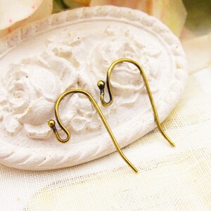May include: Two gold-toned earring hooks with a small ball at the top of each hook.