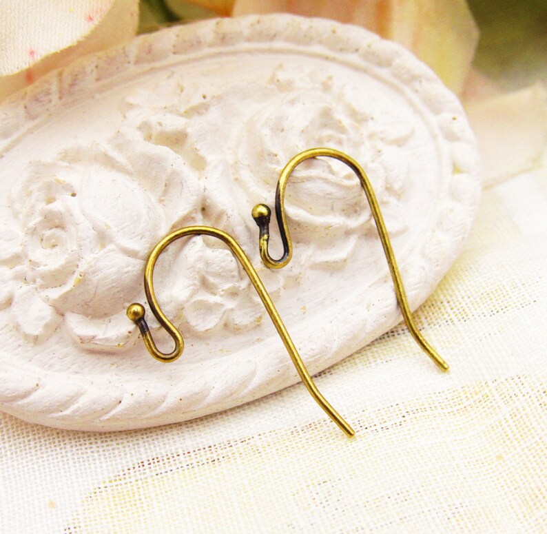 May include: Two gold-toned earring hooks with a small ball at the top of each hook.