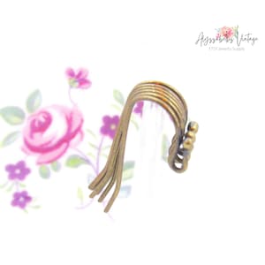 May include: A set of six antique gold-toned metal earring hooks. The hooks are stacked on top of each other and have a slight curve.