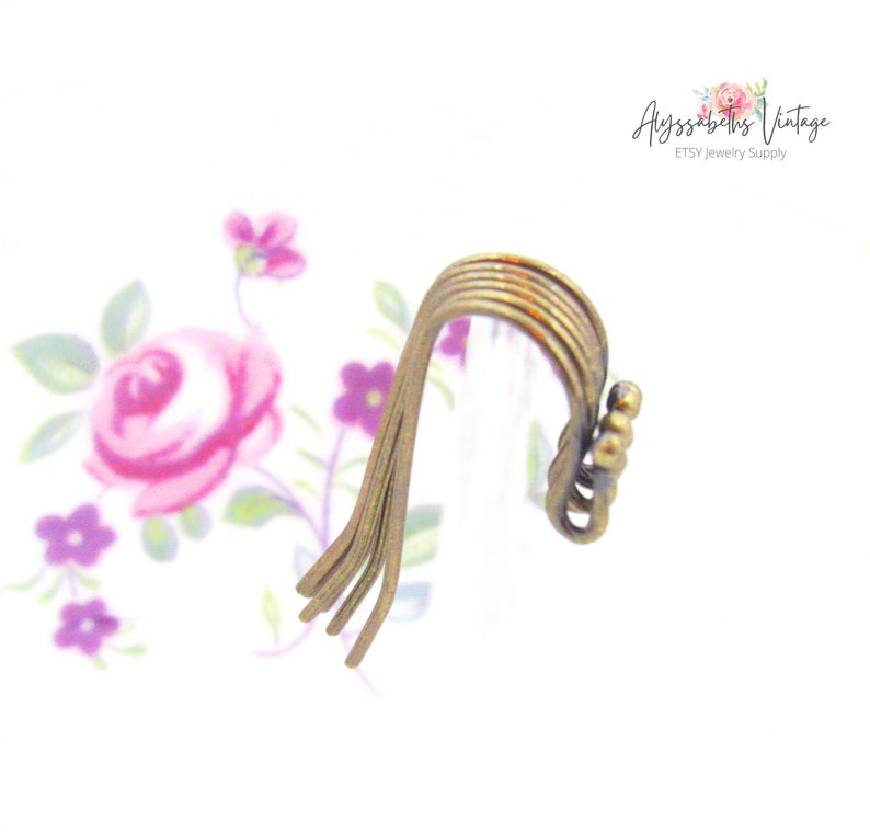 May include: A set of six antique gold-toned metal earring hooks. The hooks are stacked on top of each other and have a slight curve.