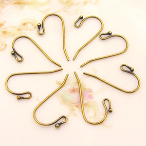 May include: Eight antique brass earring hooks with a rounded loop at the top and a small ball at the bottom.