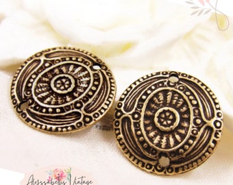 May include: Two antique gold-toned metal round decorative embellishments with intricate embossed designs. Each piece has two holes for attaching.
