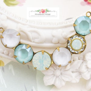 May include: A gold-tone metal connector with a row of six faceted glass beads. The beads are in a mix of white and light blue.