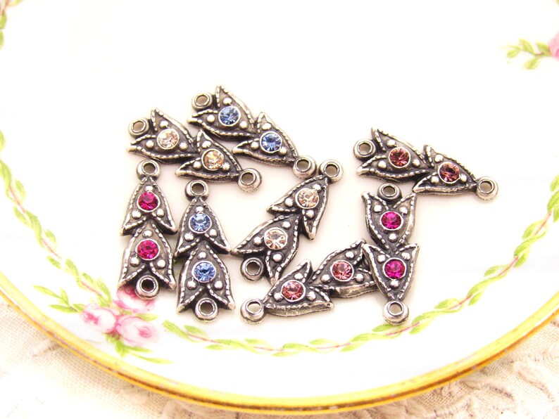 May include: Assortment of silver-toned metal pendant charms with crystal embellishments. Each charm features a teardrop shape with three rows of crystals in various colors, including pink, blue, and clear.