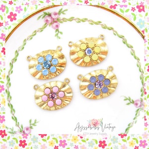May include: Four gold-toned oval-shaped metal charms with a flower design. Each charm has a different colored center stone: yellow, blue, pink, and purple.