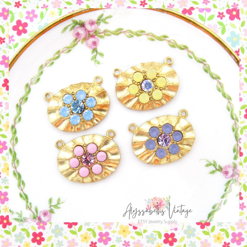 May include: Four gold-toned oval-shaped metal charms with a flower design. Each charm has a different colored center stone: yellow, blue, pink, and purple.