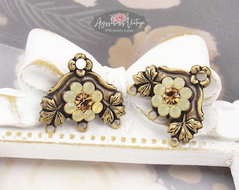 Puede incluir: Dos adornos metálicos de color dorado antiguo con un diseño floral. Cada adorno presenta un grupo de piedras de cristal de color amarillo pálido con una sola piedra de cristal ámbar en el centro. Los adornos tienen tres lazos para sujetar a joyas u otras manualidades.