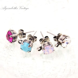 May include: Four pairs of silver stud earrings with different colored gemstones. The gemstones are pink, turquoise, white, and clear.