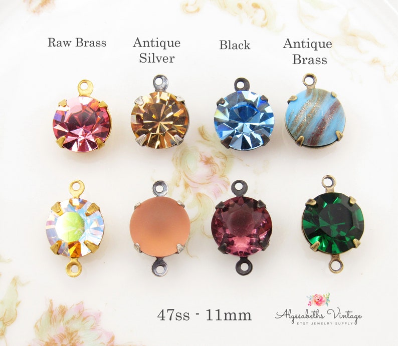 May include: Assortment of 11mm round glass rhinestones with different colors and finishes. Each rhinestone is attached to a metal connector with a loop on each side. The connectors are available in raw brass, antique silver, black, and antique brass finishes. The text "47ss - 11mm" is visible at the bottom of the image.