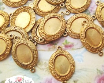 Puede incluir: Un conjunto de engastes de colgantes ovalados dorados con detalles florales y geométricos ornamentados. Cada engaste tiene un lazo en la parte superior e inferior para sujetarlo a una cadena u otro componente de joyería. Los engastes son para la fabricación de joyas.