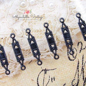 May include: Six black metal connector pieces with an ornate design. Each piece has two loops at the top and bottom.